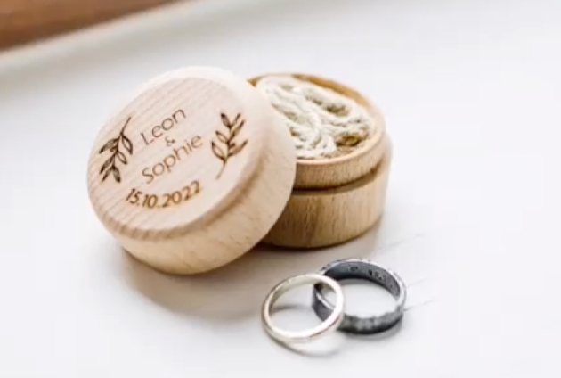 engraved wooden ring box with two rings in it