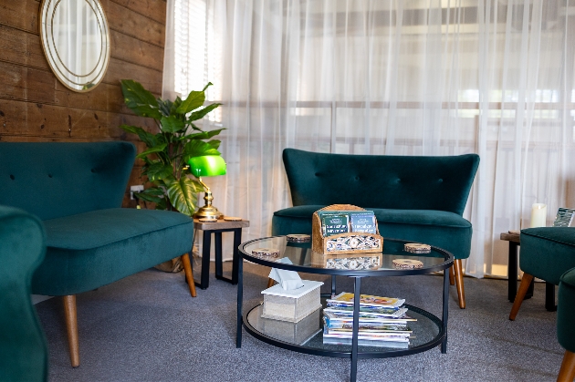 green sofa and armchairs in an area with mags on the table
