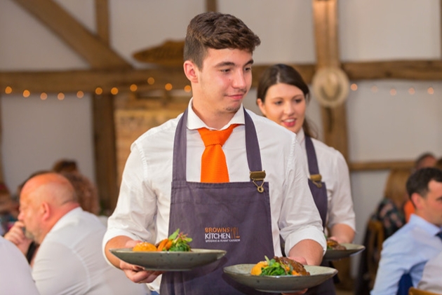 waiter carrying in two dishes to an event