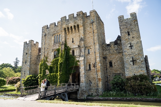 A bride and groom standing in front of a large castle