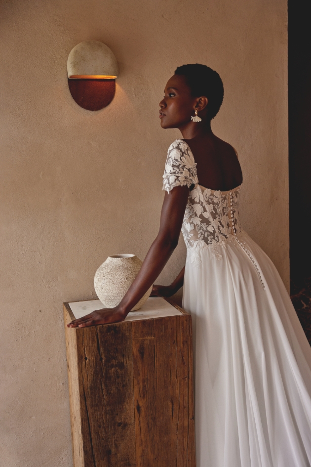 woman leaning on wooden block in lacey dress