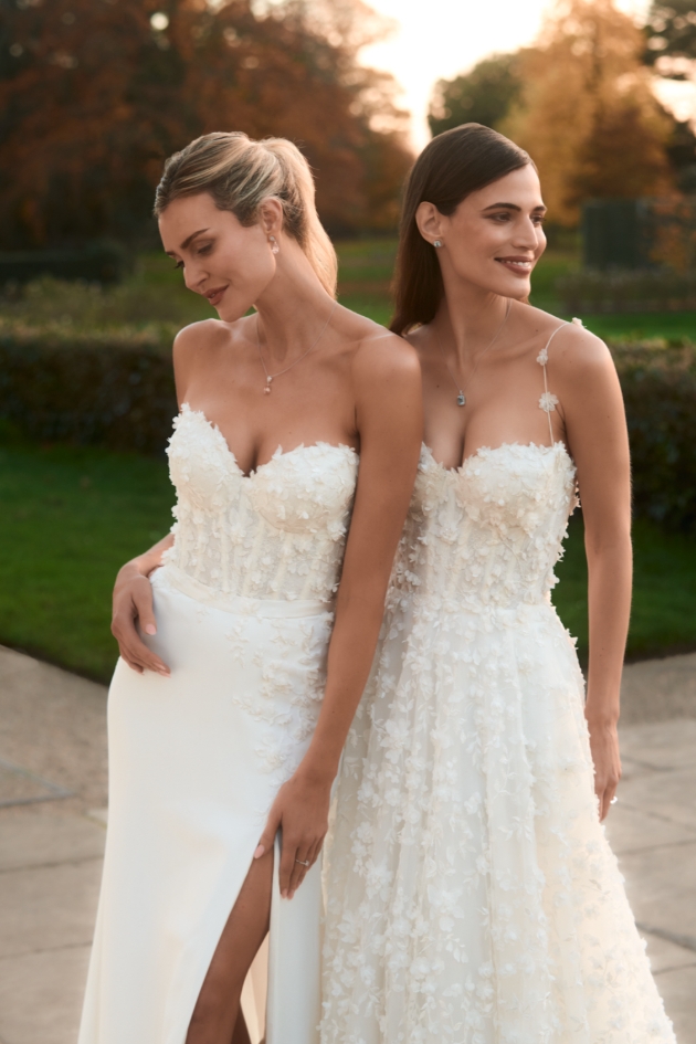two women in wedding dresses posing at sunset