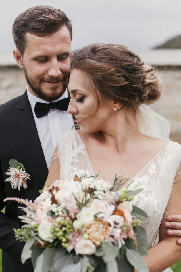 couple on wedding day bride holding bouquet peach in colour
