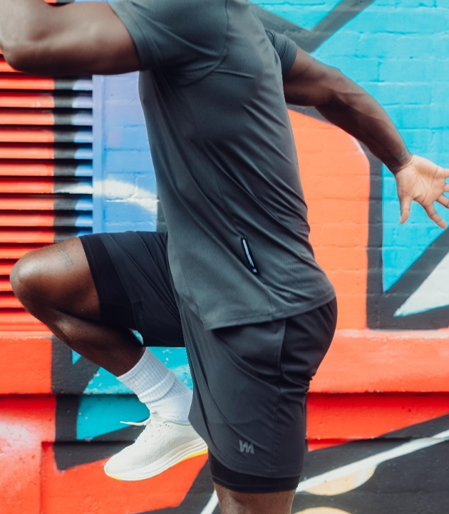 man doing exercise in front of a graffitied wall