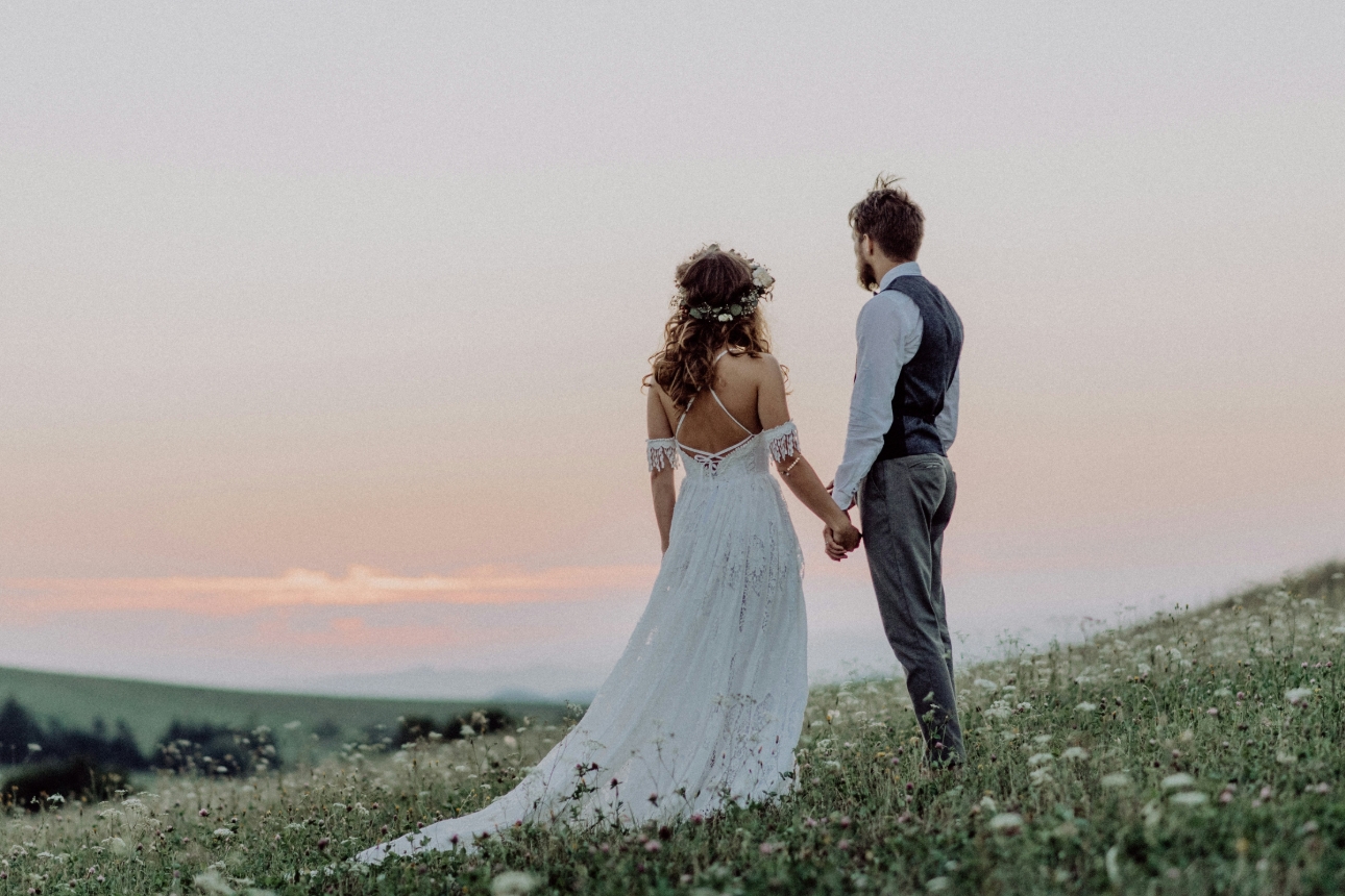 bride and groom standing in a field 