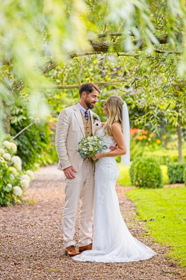 A bride and groom looking at each other underneath a tree