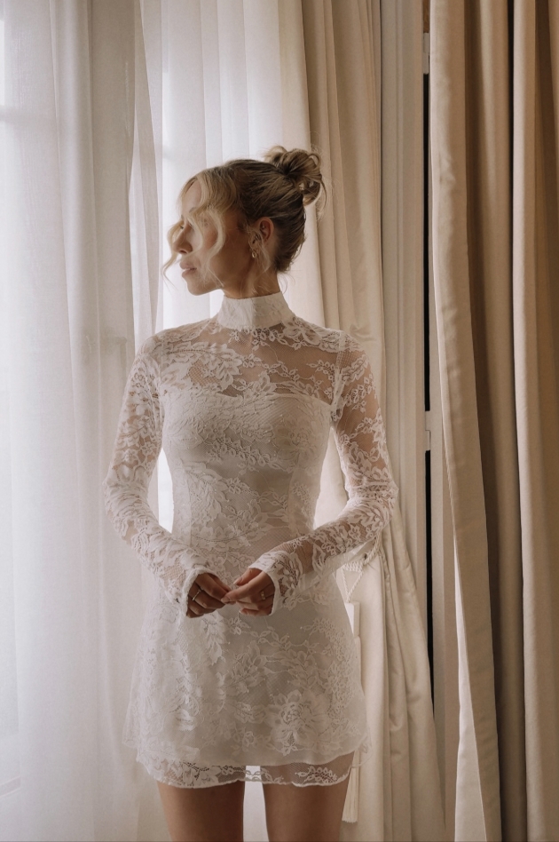 model in high necked sleeved short skirt dress in lace