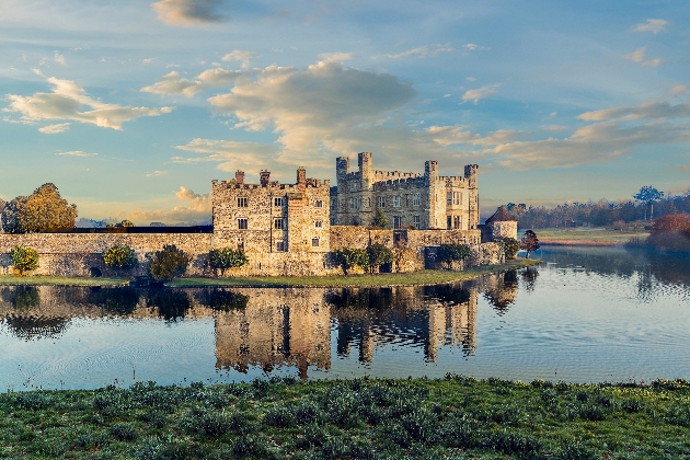 The exterior of a grand castle surrounded by water