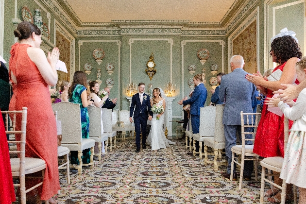 A bride and groom walking down the aisle surrounded by friends and family
