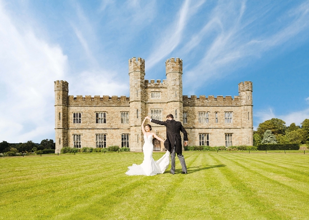 A bride and groom dancing in front of a castle