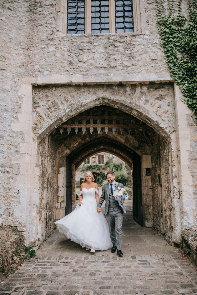 A bride and groom walking through a castle gate
